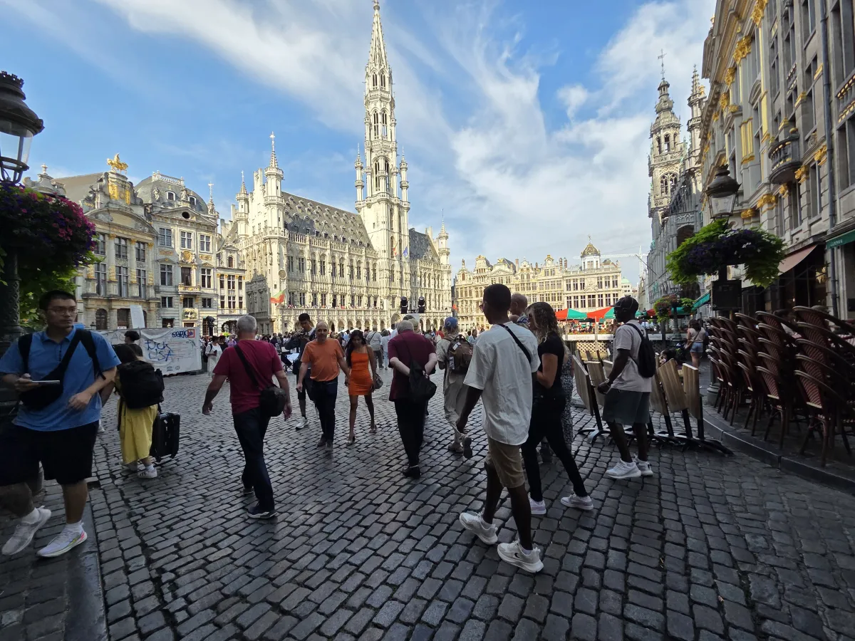 Crowds on the cobblestones of the Grand Place at golden hour